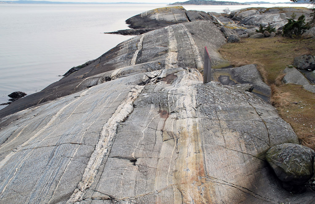 En klippa av gnejs med typiska ränder i olika grå nyanser.