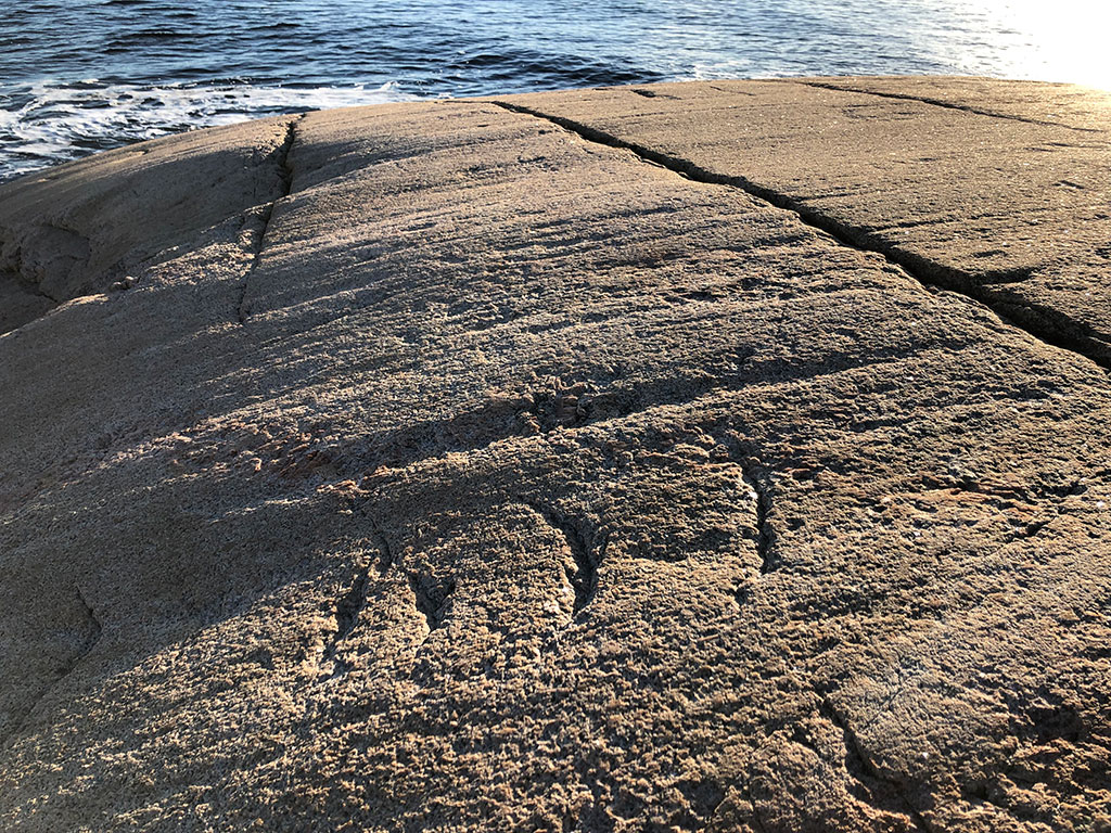 En solbelyst klippa av granit med tydliga räfflor skapat av inlandsisen för tusentals år sedan.