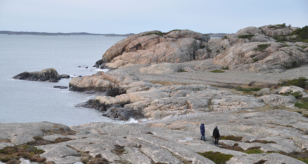 Två personer går på de kala klipporna på västsidan av Saltö.